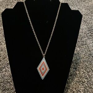 INC gold tone necklace with medallion. White, coral & pale blue beads.